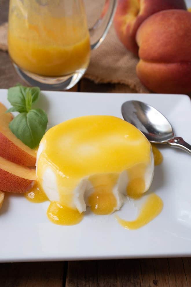 Panna cotta with some bites taken and peach sauce dripping
