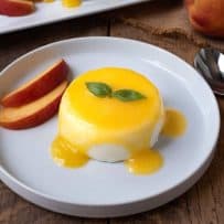 Panna cotta served on a plate with peach sauce