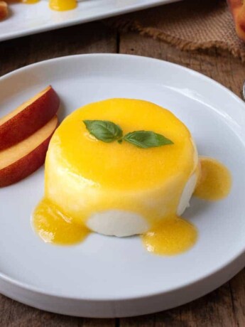 Panna cotta served on a plate with peach sauce