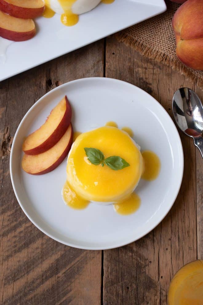 Panna cotta with peach sauce, peach slices and basil leaves