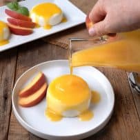 Pouring peach sauce over panna cotta