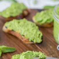 Small slices of crusty bread spread with green pea and mint peso