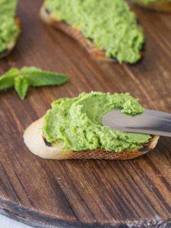 Spreading pea and mint pesto onto a crostini