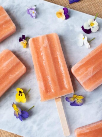 Lovely peach colored popsicles (ice lollies) with pretty flowers for decoration