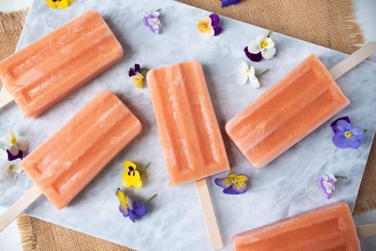 Lovely peach colored popsicles (ice lollies) with pretty flowers for decoration