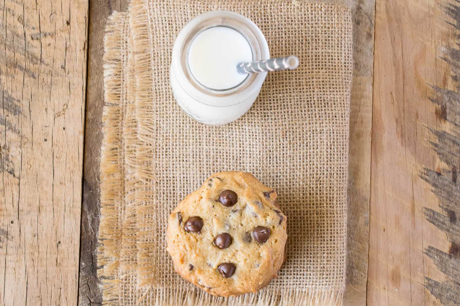 A cookie and bottle of milk from overhead ready to enjoy