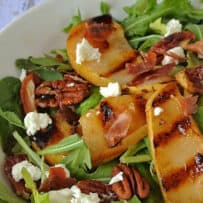 Creamy pieces of white goat cheese on top of sliced pears, pecans and arugula