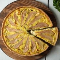A slice of quiche cut served on a round wood board