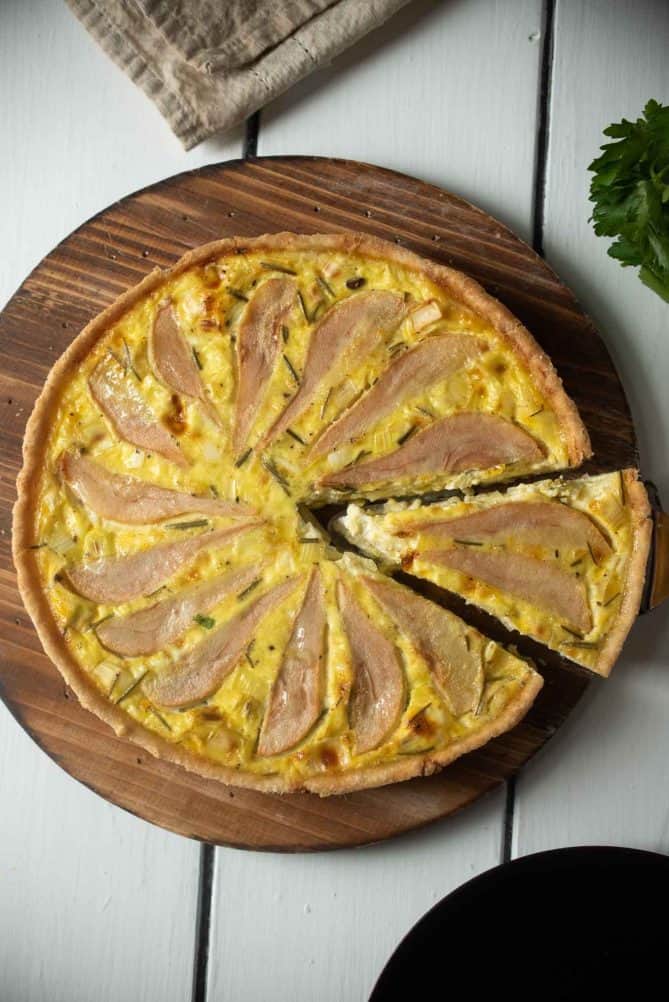 A slice of quiche cut served on a round wood board