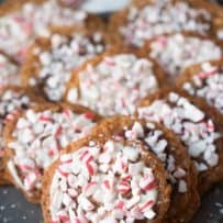 Peppermint Florentine cookies decorated with crushed candy canes on a grey plate