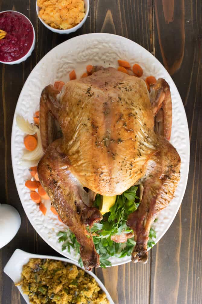 A roasted turkey on an oval platter with vegetables