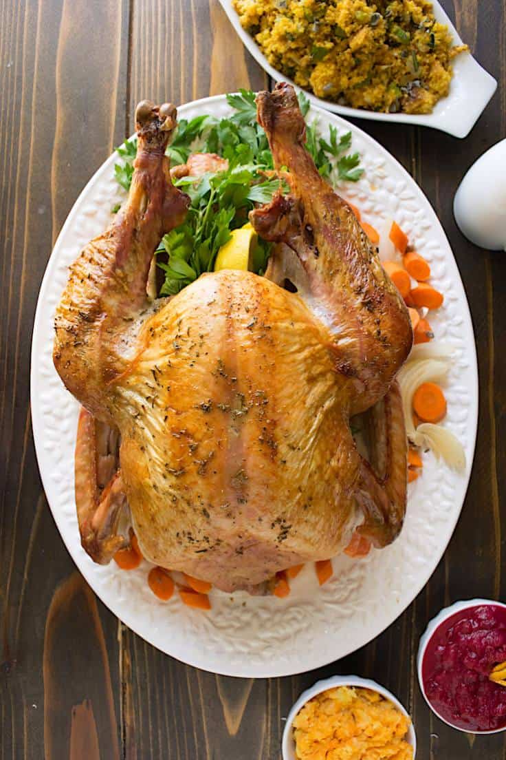 A perfectly roasted turkey surrounded by carrots and parsley