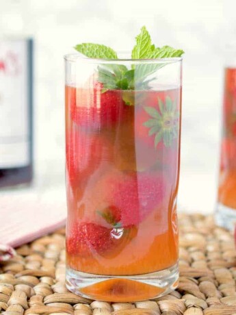 A side view of 2 glasses Pimm's strawberry mint cocktail showing all the strawberries in the glass