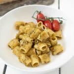 A bowl of pistachio pesto pasta with cherry tomatoes on the vine