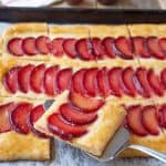 Lifting a slice of plum tart with a cake slicer