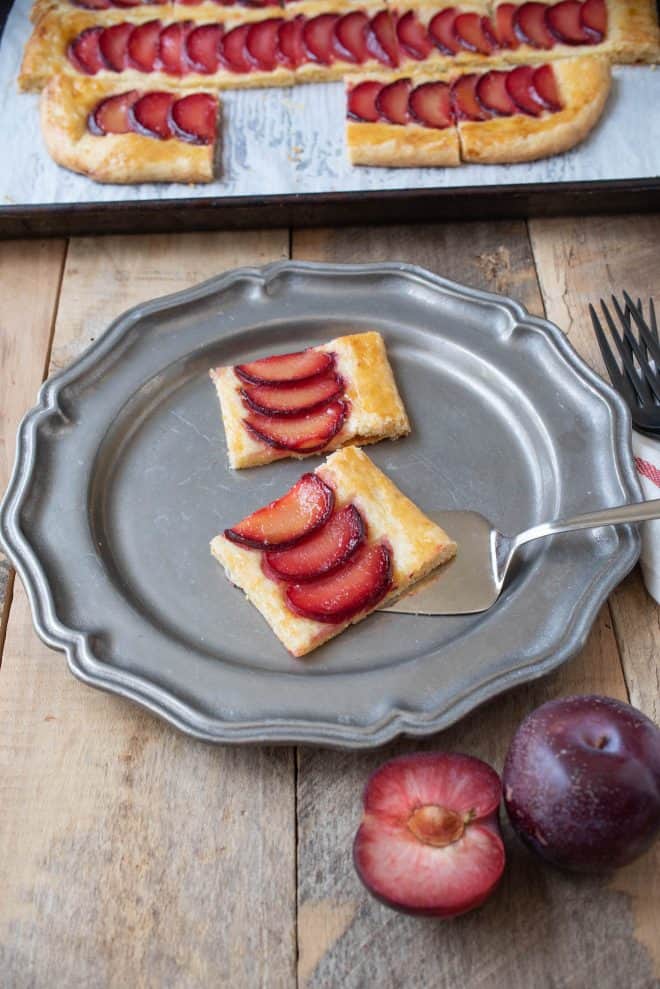 2 squares of plum tart on a pewter plate