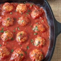 A cast iron skillet with meatballs in tomato sauce