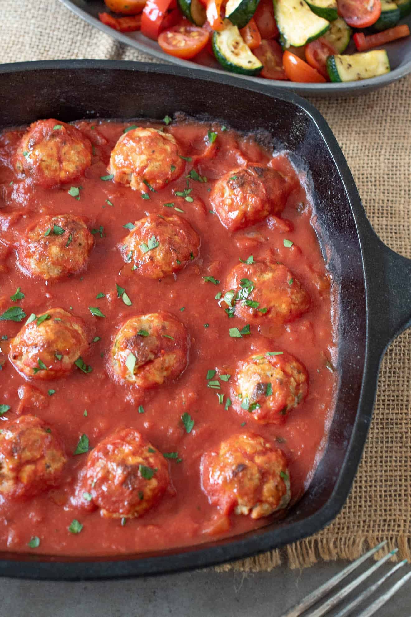 A cast iron skillet with meatballs in tomato sauce