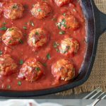 A pan of meatballs and tomato sauce and a meatball on a fork