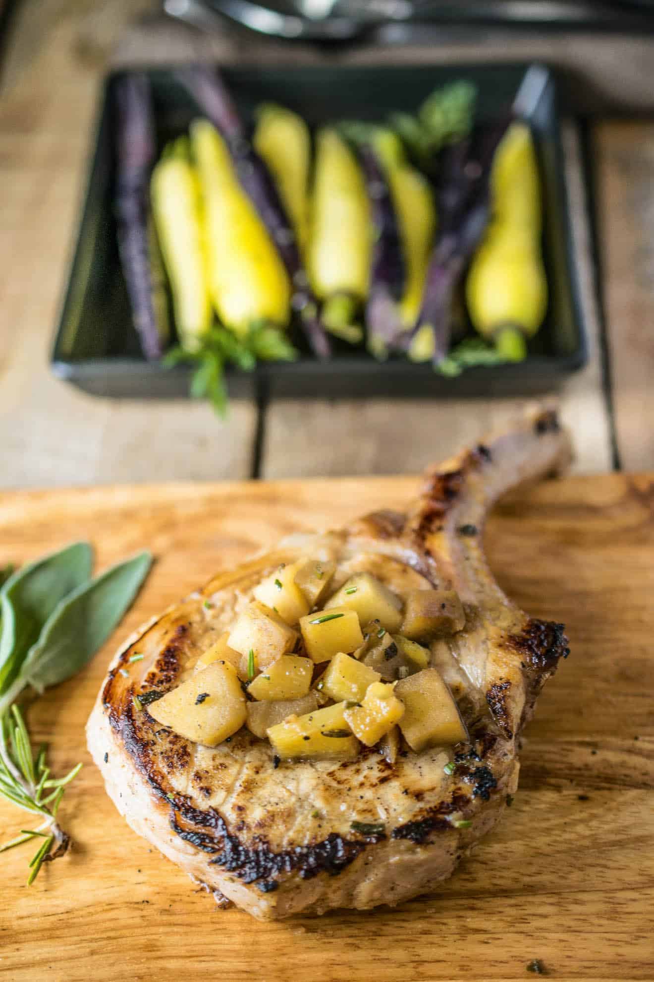 A pork chop on a cutting board topped with chopped apples