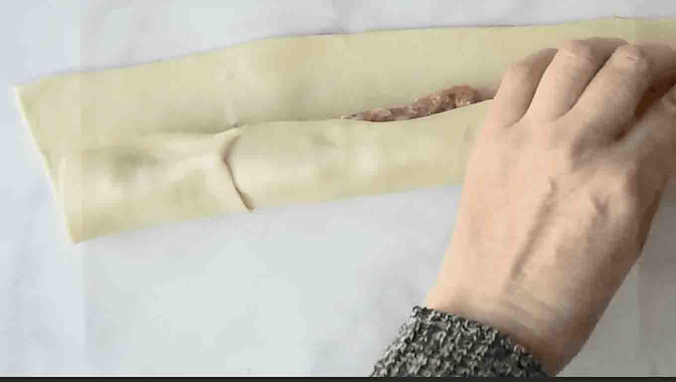 Rolling puff pastry around sausage