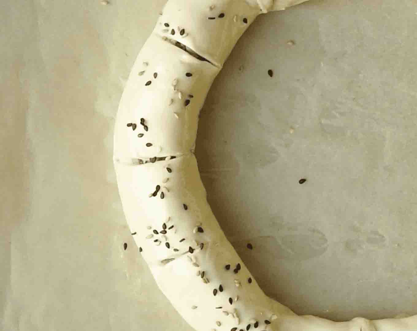 Sprinkling sesame seeds onto sausage roll