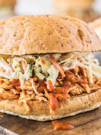 A side view of pulled chicken piled onto a bun and topped with coleslaw