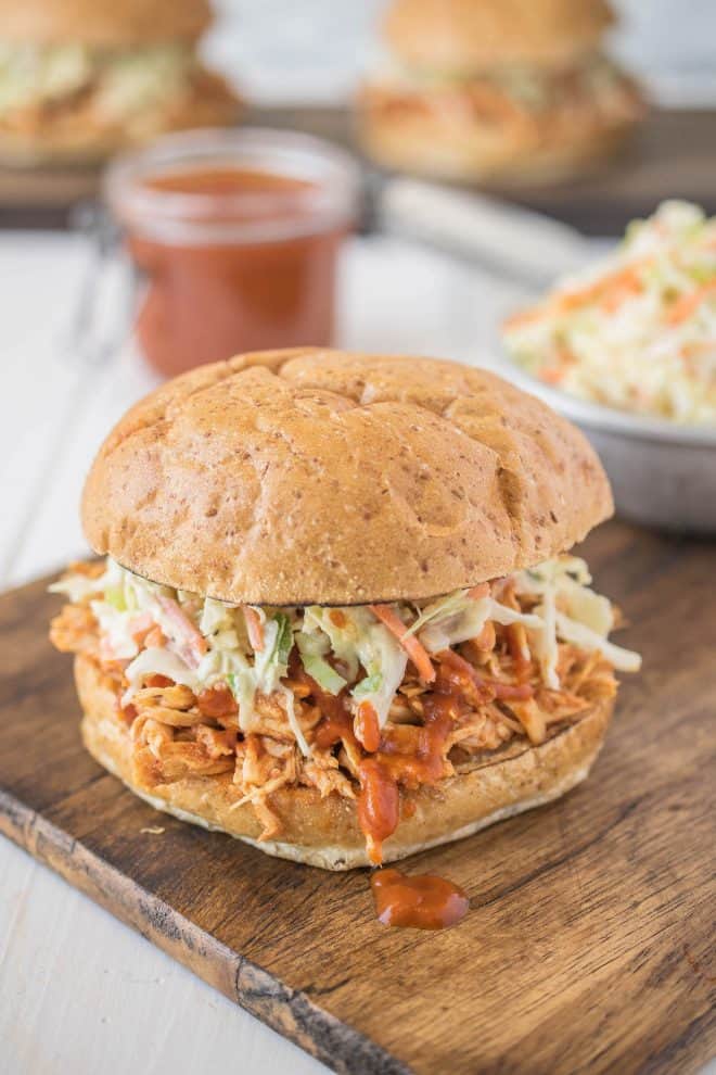Pulled chicken in a sandwich bun topped with barbecue sauce and coleslaw