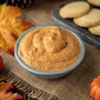 The dip is served in a grey bowl surrounded by shortbread cookies, maple leaves and mini pumpkins