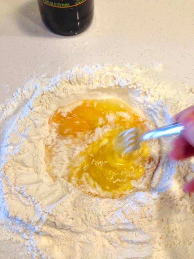 The start of making pasta. Whisking eggs into flour