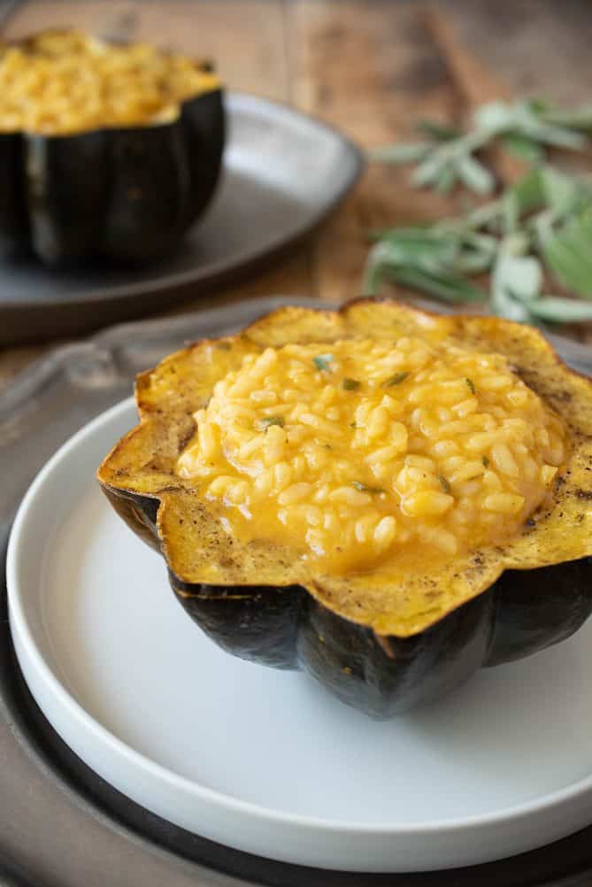 A side view of pumpkin risotto stuffed acorn squash with another in the background