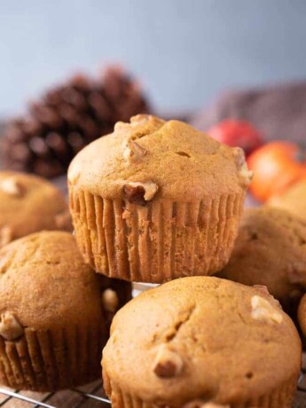 A pumpkin walnut muffin on top of other muffins
