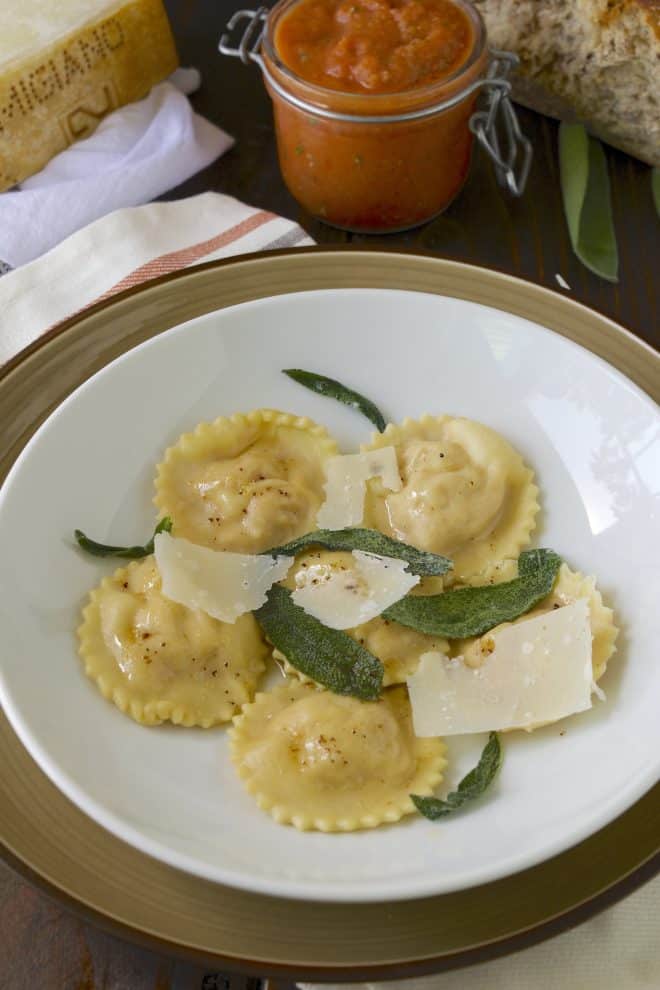Pumpkin ricotta ravioli on a plate with crusty bread and cheese