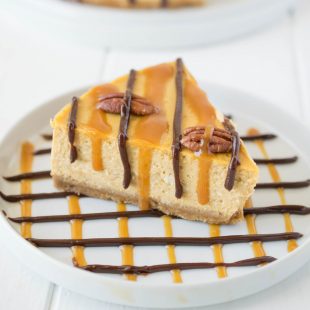 A white plate decorated with chocolate and caramel with a slice of pumpkin turtle cheesecake