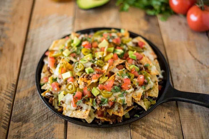 A round pan holding a pile of queso fundido nachos