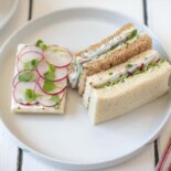A closeup of 1 open faced radish sandwich and 2 crustless sandwiches