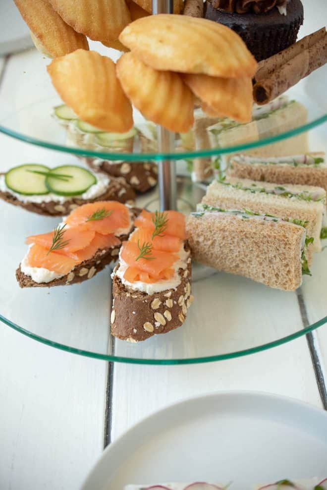 A selection of sandwiches on a tiered tray. Salmon and cream cheese, radish and herb butter