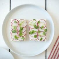 2 open-faced radish and herb butter sandwiches topped with micro greens