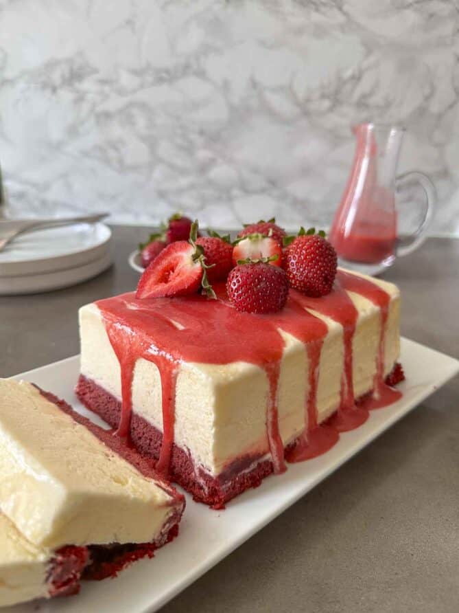 Semifreddo in the shape of a loaf cake topped with fresh strawberry sauce and strawberries