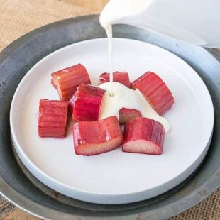 Baked rhubarb on a white plate with English custard