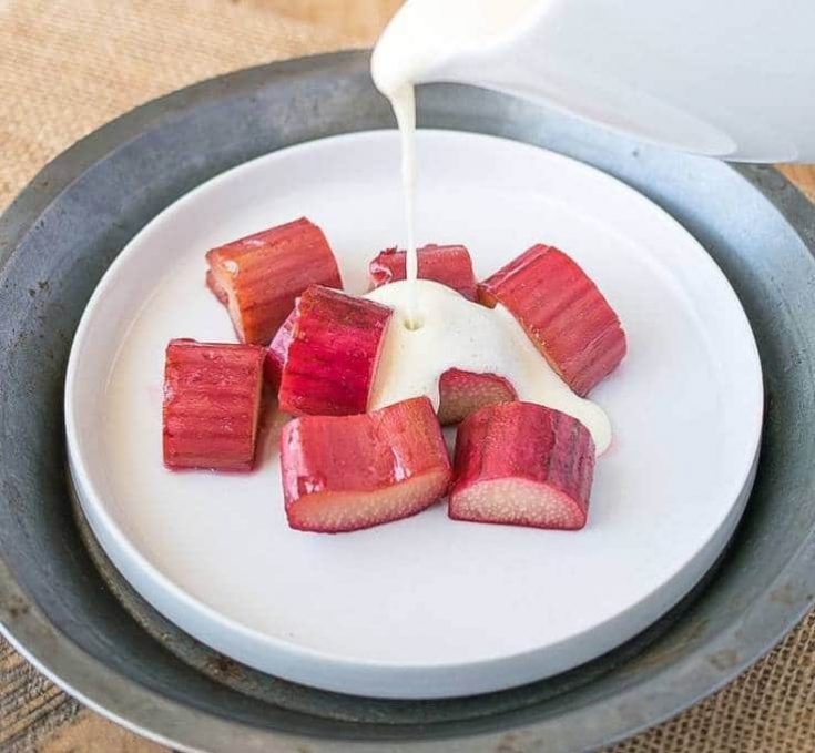 Baked rhubarb on a white plate with English custard