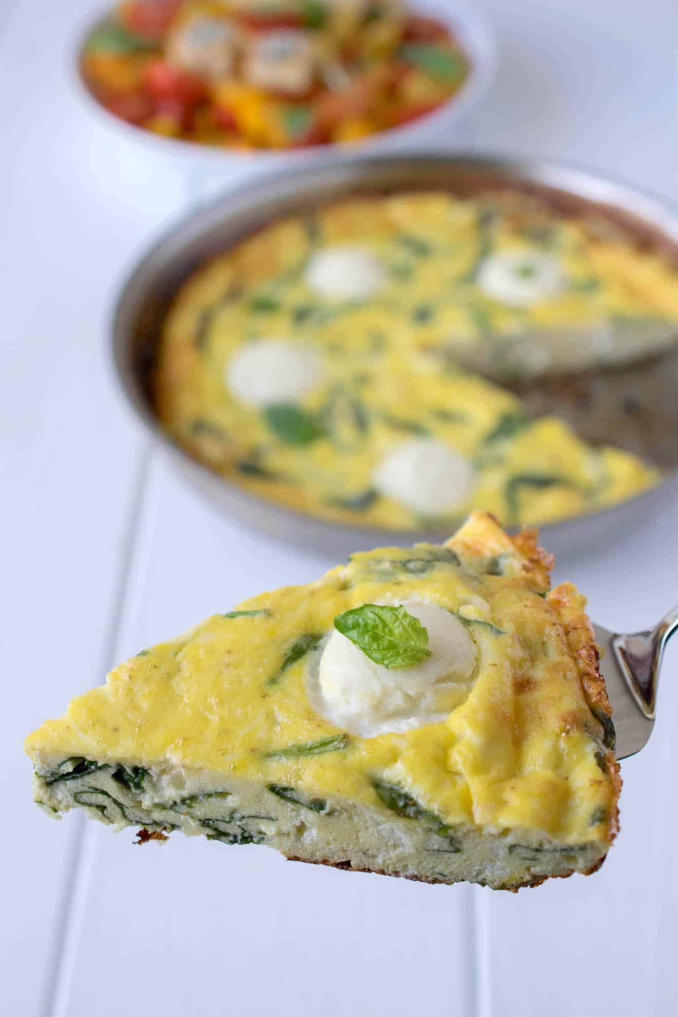 A slice of frittata with flecks of spinach inside and ricotta on the top