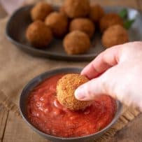 Dipping a risotto rice ball into tomato sauce