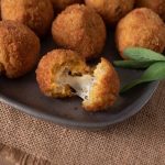 A risotto rice ball opened up to reveal the cheesy center