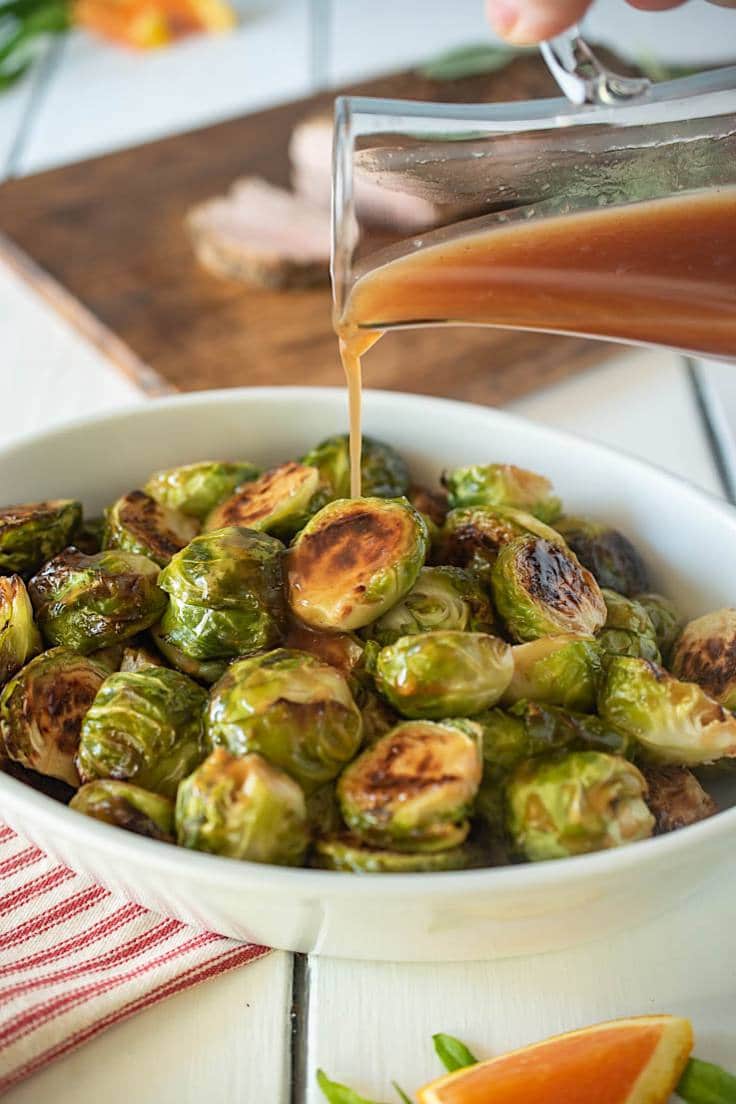 Cranberry glaze being drizzled over roasted Brussels sprouts