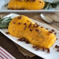 A half of a butternut squash, sliced and topped with pecans