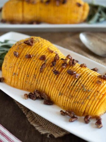 A half of a butternut squash, sliced and topped with pecans