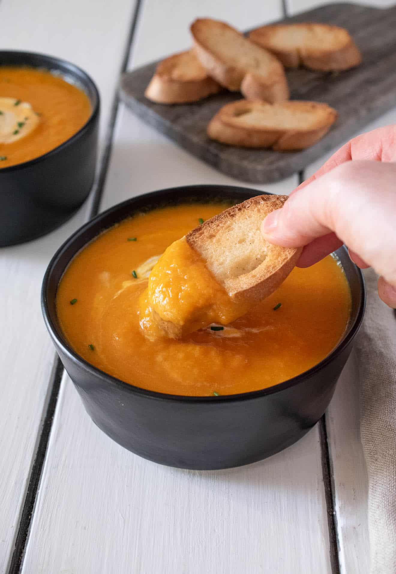 Dipping bread into Roasted Carrot Ginger Soup
