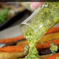 Different color carrots roasted on a plate topped with pesto