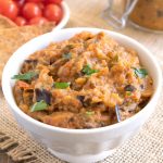 Roasted eggplant dip in a white bowl garnished with fresh parsley